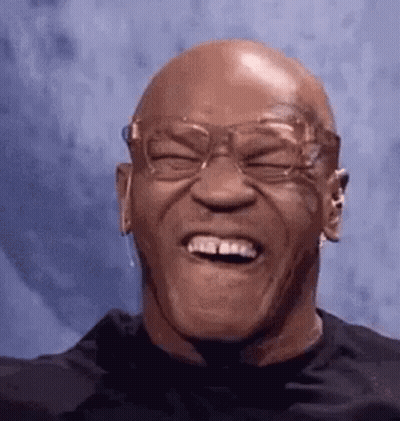 A Bald Man Wearing Glasses Is Laughing With His Eyes Closed And His Mouth Open . GIF