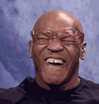 A Bald Man Wearing Glasses Is Laughing With His Eyes Closed And His Mouth Open . GIF