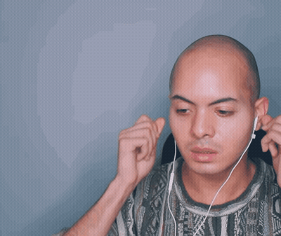A Bald Man Wearing Headphones And A Patterned Shirt Waves His Hand In The Air GIF