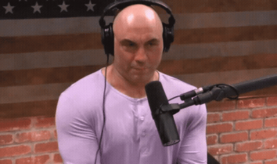 A Bald Man Wearing Headphones And A Purple Shirt Is Sitting In Front Of A Microphone GIF