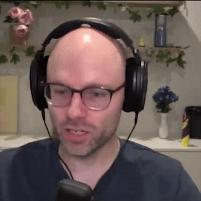 A Bald Man Wearing Headphones And Glasses Is Talking Into A Microphone GIF