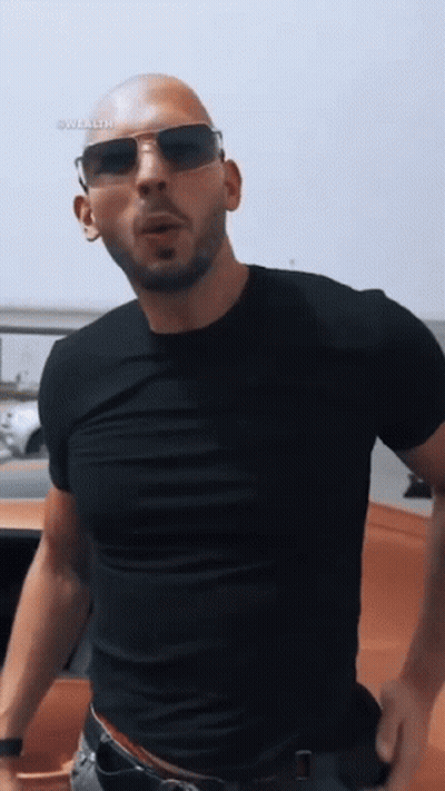 A Bald Man Wearing Sunglasses And A Black T-Shirt GIF