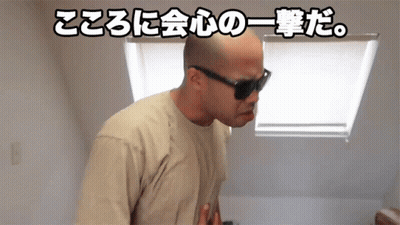 A Bald Man Wearing Sunglasses And A Tan Shirt Is Standing In Front Of A Window With Chinese Writing Behind Him GIF