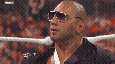 A Bald Man Wearing Sunglasses Is In A Wrestling Ring . GIF