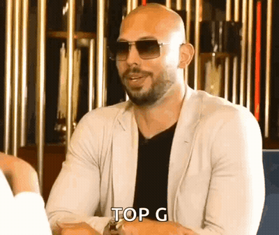 A Bald Man Wearing Sunglasses Is Sitting At A Table And Says Top G . GIF
