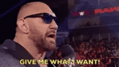 A Bald Man Wearing Sunglasses Is Talking Into A Microphone And Says `` Give Me What I Want ! '' GIF