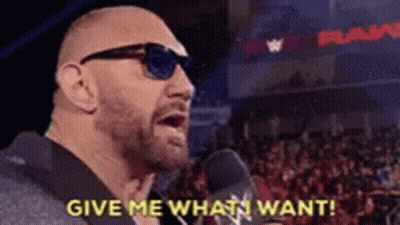 A Bald Man Wearing Sunglasses Is Talking Into A Microphone And Says `` Give Me What I Want '' . GIF