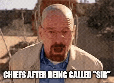 A Bald Man With A Beard And Glasses Is Standing In The Desert And Talking . GIF