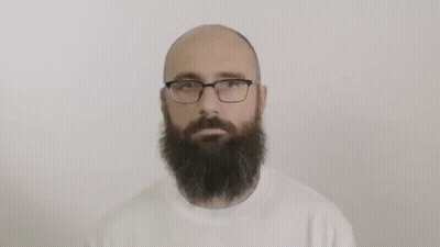 A Bald Man With A Beard And Glasses Is Wearing A White Sweater . GIF