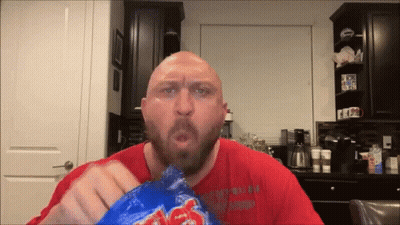 A Bald Man With A Beard Is Eating A Bag Of Lays Chips GIF