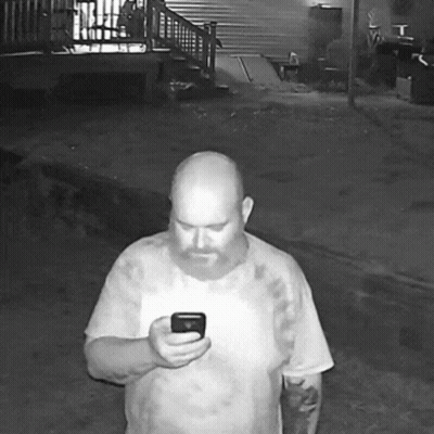 A Bald Man With A Beard Is Holding A Cell Phone GIF