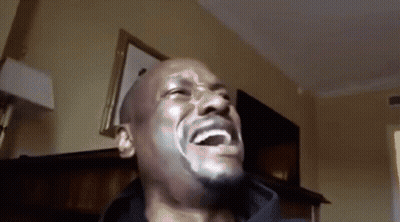 A Bald Man With A Beard Is Laughing In A Room GIF
