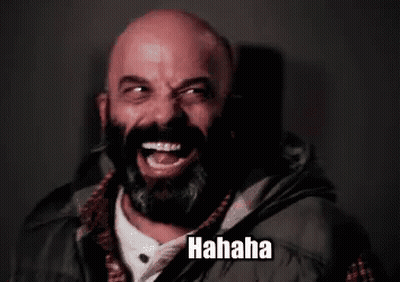 A Bald Man With A Beard Is Laughing While Wearing A Vest . GIF
