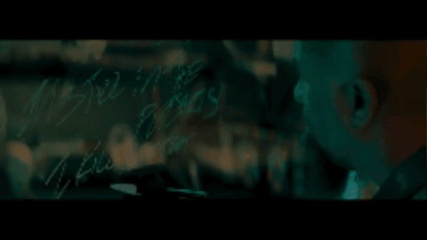 A Bald Man With A Beard Is Looking At Something In A Dark Room GIF