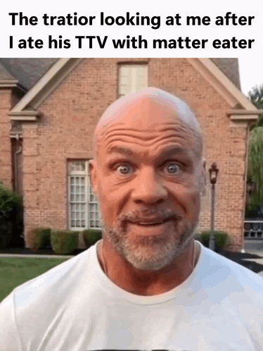 A Bald Man With A Beard Is Looking At The Camera In Front Of A Brick Building . GIF