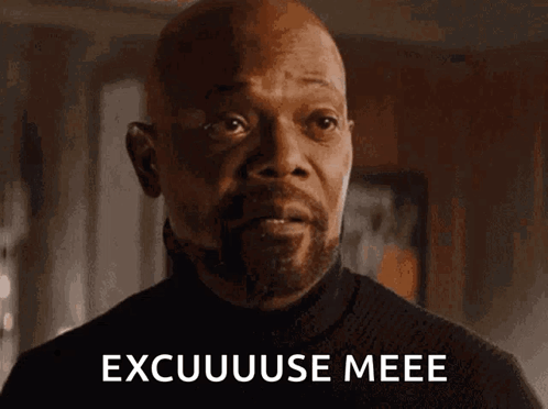A Bald Man With A Beard Is Looking At The Camera With The Words Excuuuse Meee Written On His Face . GIF