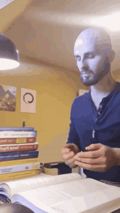 A Bald Man With A Beard Is Reading A Book GIF