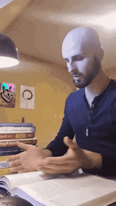 A Bald Man With A Beard Is Reading A Book In Front Of A Stack Of Books . GIF