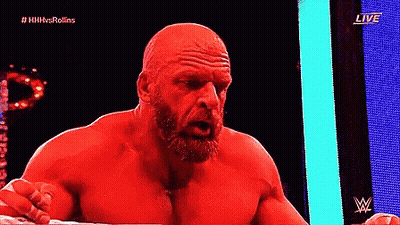 A Bald Man With A Beard Is Standing In A Ring With A Live Sign Behind Him GIF
