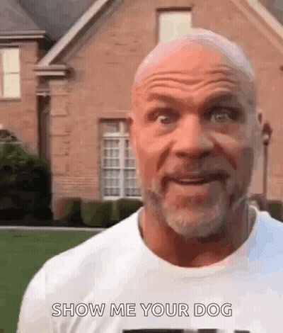 A Bald Man With A Beard Is Standing In Front Of A Brick House And Saying Show Me Your Dog . GIF