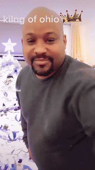 A Bald Man With A Beard Is Standing In Front Of A Christmas Tree With The Words King Of Ohio Above Him GIF