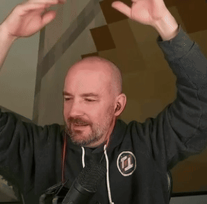 A Bald Man With A Beard Is Standing In Front Of A Microphone . GIF