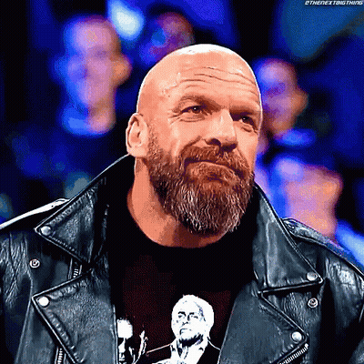A Bald Man With A Beard Is Wearing A Black Shirt And A Leather Jacket GIF