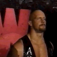 A Bald Man With A Beard Is Wearing A Black Tank Top And Standing In Front Of A Red Wall . GIF