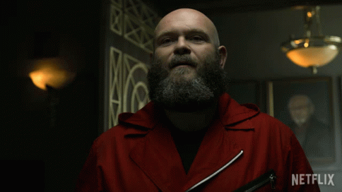 A Bald Man With A Beard Is Wearing A Red Jacket That Says Netflix On It GIF