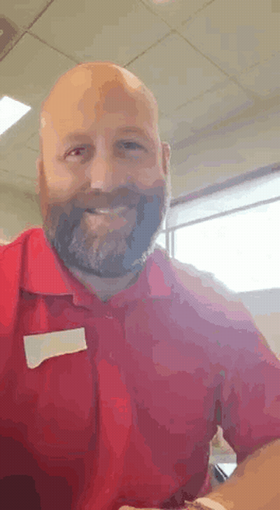 A Bald Man With A Beard Is Wearing A Red Shirt . GIF