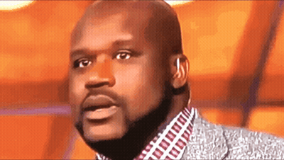 A Bald Man With A Beard Is Wearing A Suit And Ear Buds GIF