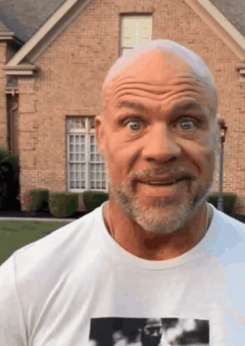 A Bald Man With A Beard Is Wearing A White T-Shirt With A Picture Of A Man On It GIF