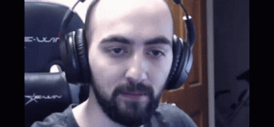 A Bald Man With A Beard Is Wearing Headphones And Making A Funny Face . GIF