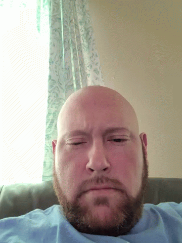 A Bald Man With A Beard Laying On His Back With His Eyes Closed GIF