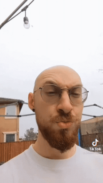A Bald Man With A Beard Wearing Glasses And A White Shirt . GIF