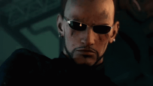 A Bald Man With A Beard Wearing Sunglasses Looks At The Camera GIF
