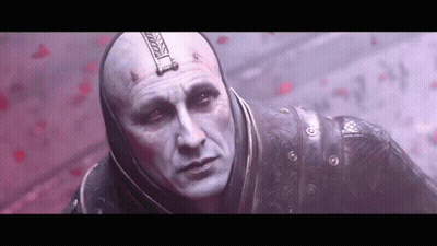 A Bald Man With A Hood On His Head Is Standing In Front Of A Red Wall . GIF