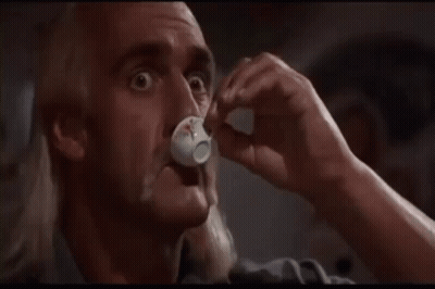 A Bald Man With A Mustache Is Drinking From A Small White Cup . GIF