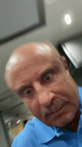 A Bald Man With A Mustache Is Making A Funny Face GIF