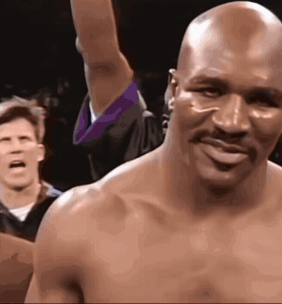 A Bald Man With A Mustache Is Smiling While A Referee Looks On GIF