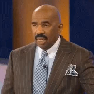 A Bald Man With A Mustache Wearing A Suit And Tie Is Making A Funny Face . GIF