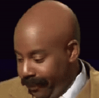 A Bald Man With A Mustache Wearing A Suit And Tie Is Making A Funny Face . GIF
