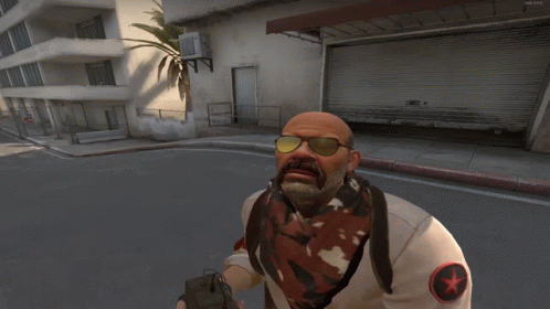 A Bald Man With A Mustache Wearing Sunglasses And A White Shirt With A Red Star On It GIF