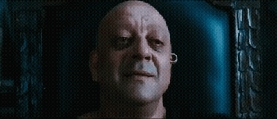 A Bald Man With A Piercing In His Ear Is Sitting In A Chair And Smiling . GIF