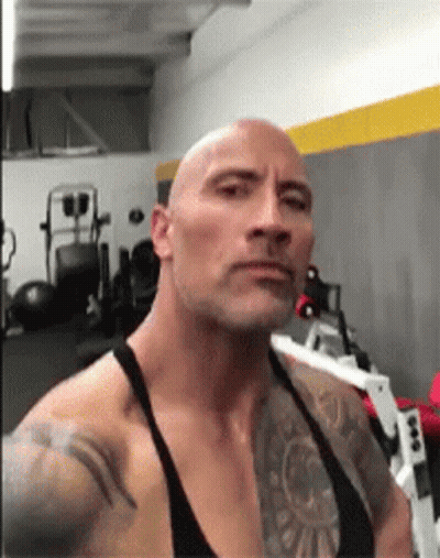 A Bald Man With A Tattoo On His Arm Is Standing In A Gym . GIF