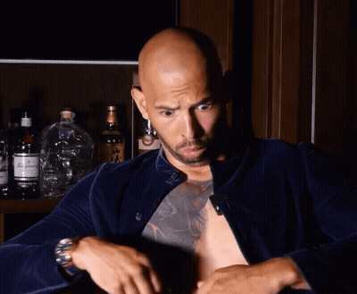 A Bald Man With A Tattoo On His Chest Holds A Bottle Of Budweiser GIF