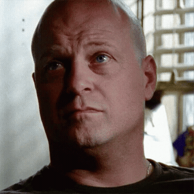 A Bald Man With Blue Eyes Looks At The Camera With A Serious Look On His Face GIF