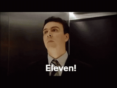 A Bald Man With Braces On His Teeth Is Looking Up At The Word Eleven GIF