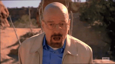 A Bald Man With Glasses And A Beard Is Standing In A Desert . GIF