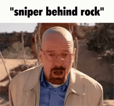 A Bald Man With Glasses And A Beard Is Standing In The Desert With The Words " Sniper Behind Rock " Written Above Him GIF